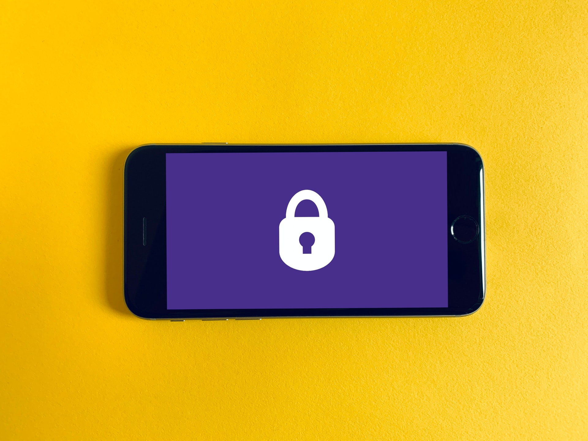 iPhone against a yellow backdrop displaying a lock symbol